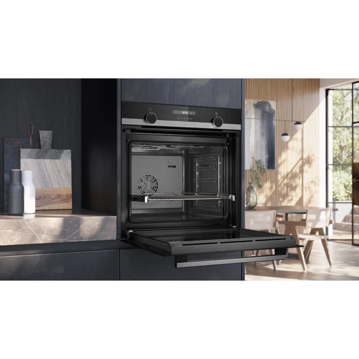 Een moderne oven met een open deur. Binnenin zijn een rooster en een ventilator zichtbaar. De keuken heeft een marmeren aanrecht en een raam met eethoek.