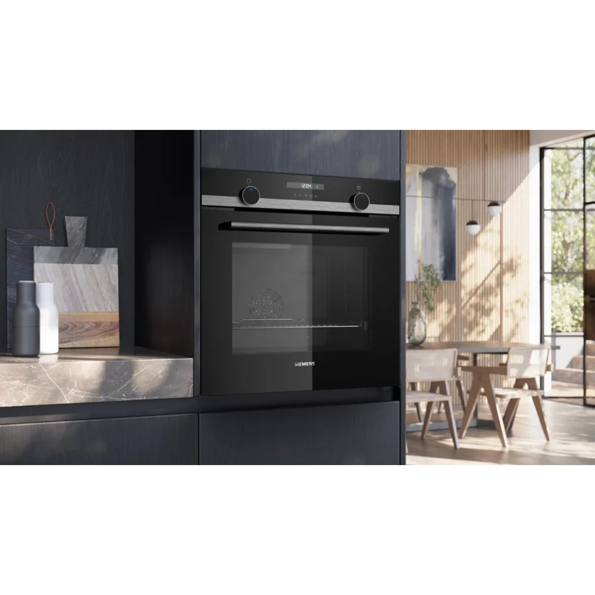 Een moderne zwarte oven ingebouwd in donkere kasten. Keukenomgeving met een eettafel en stoelen zichtbaar op de achtergrond.