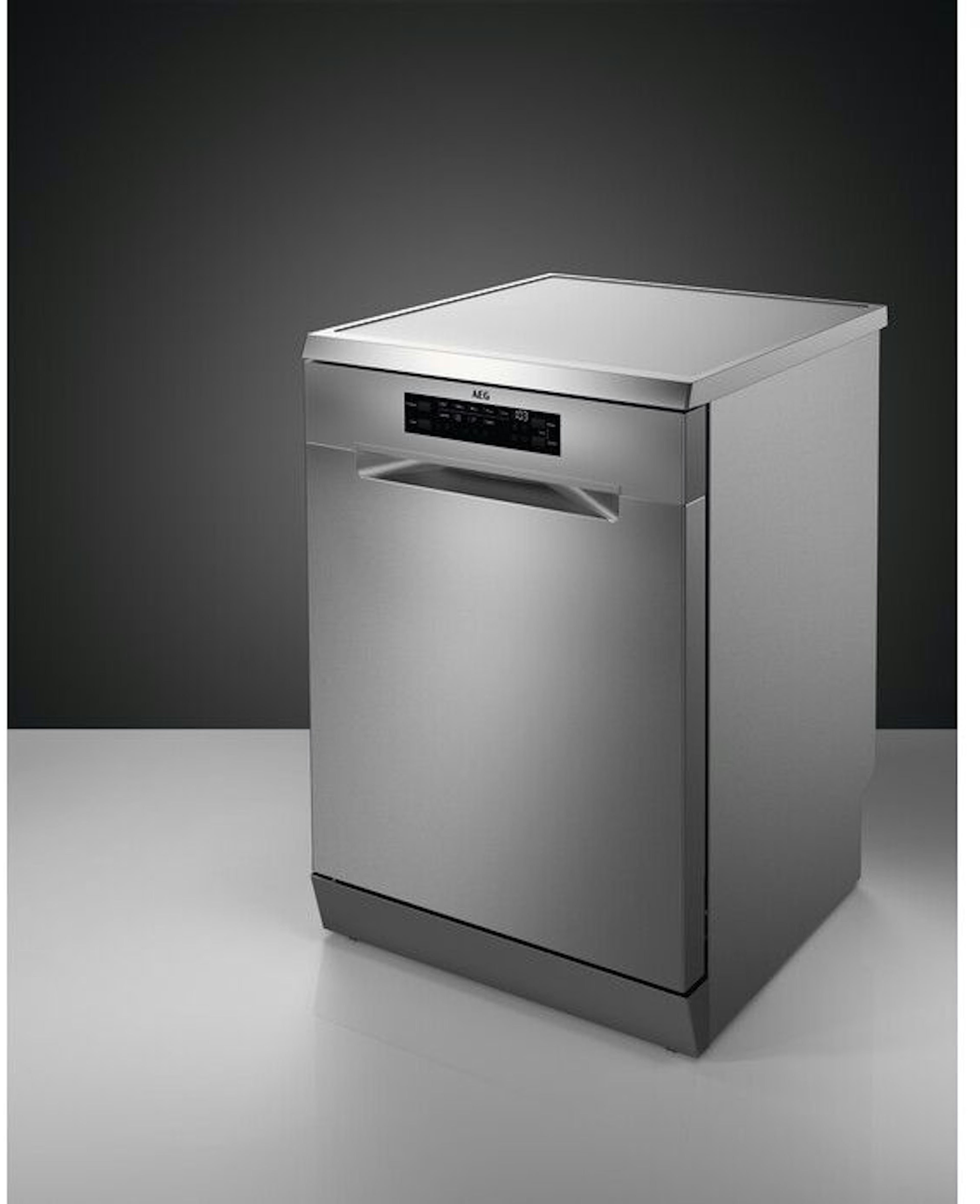 Un lave-vaisselle AEG en acier inoxydable sur une surface blanche, sur fond gris foncé.
