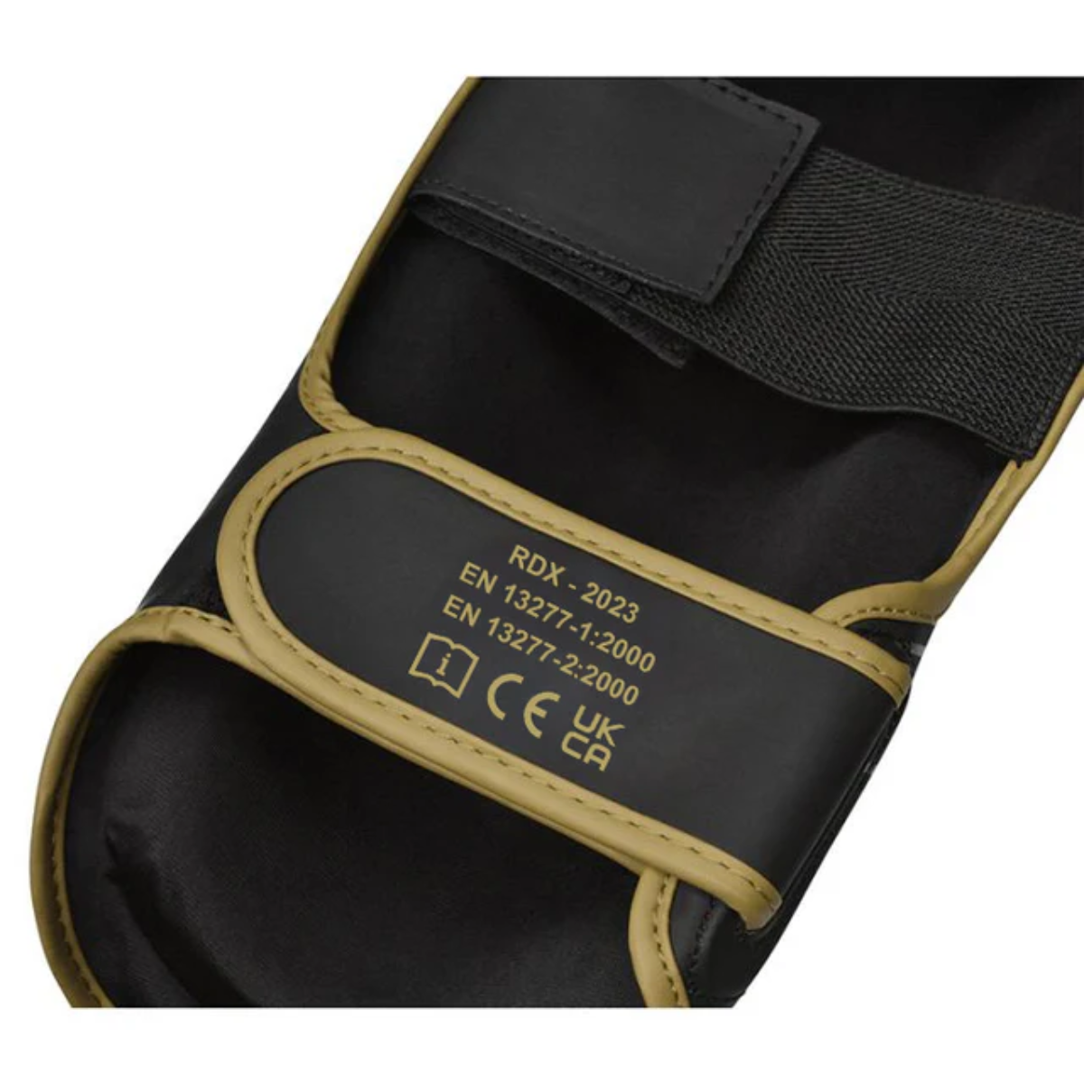 Nahaufnahme eines schwarz-goldenen Sportpads. Es hat Riemen und Text mit der Aufschrift RDX-2023, EN 13277-1:2000 und EN 13277-2:2000.