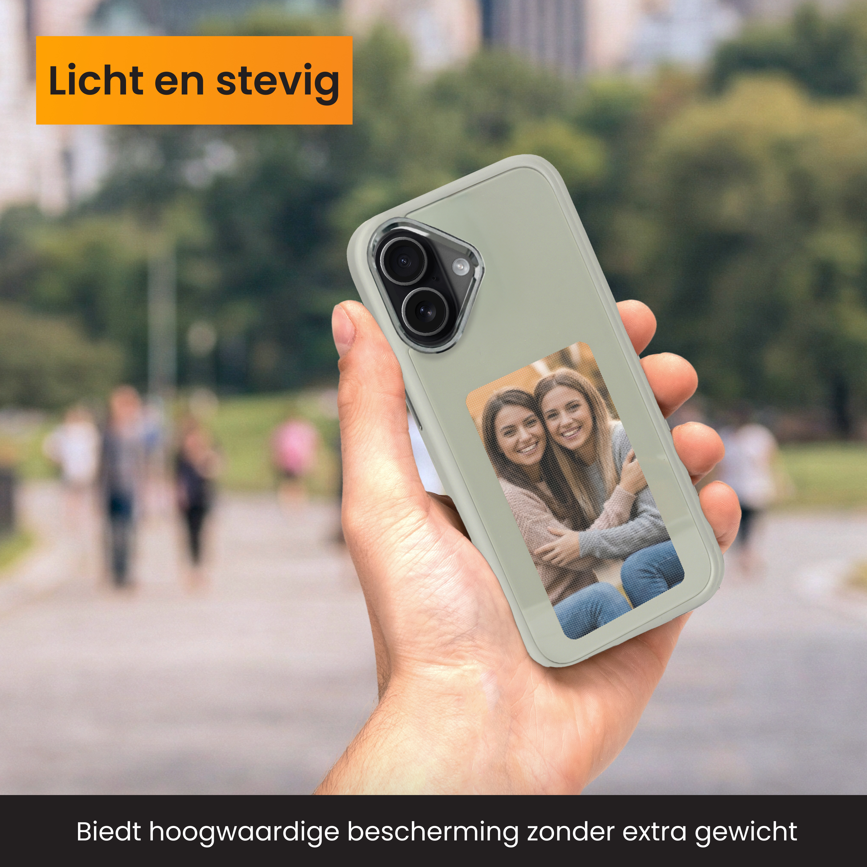 Hand die een telefoonhoes vasthoudt met een foto van twee vrouwen. Achtergrond is een vage parkscène.