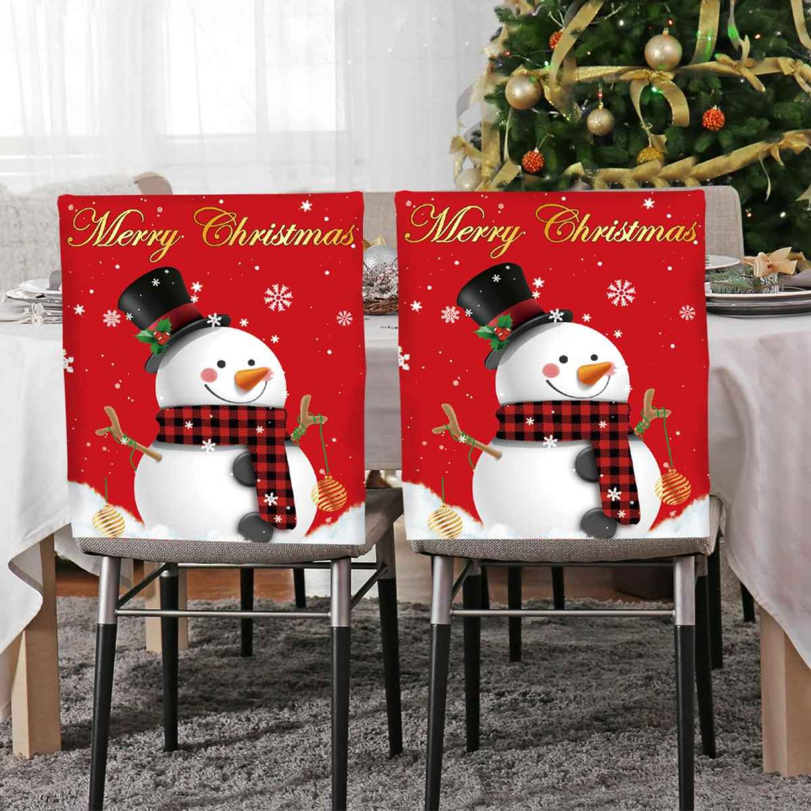Zwei Stuhlhussen mit Schneemann-Design. Roter Hintergrund, schwarzer Zylinder, Schal. Weihnachtsbaum im Hintergrund.