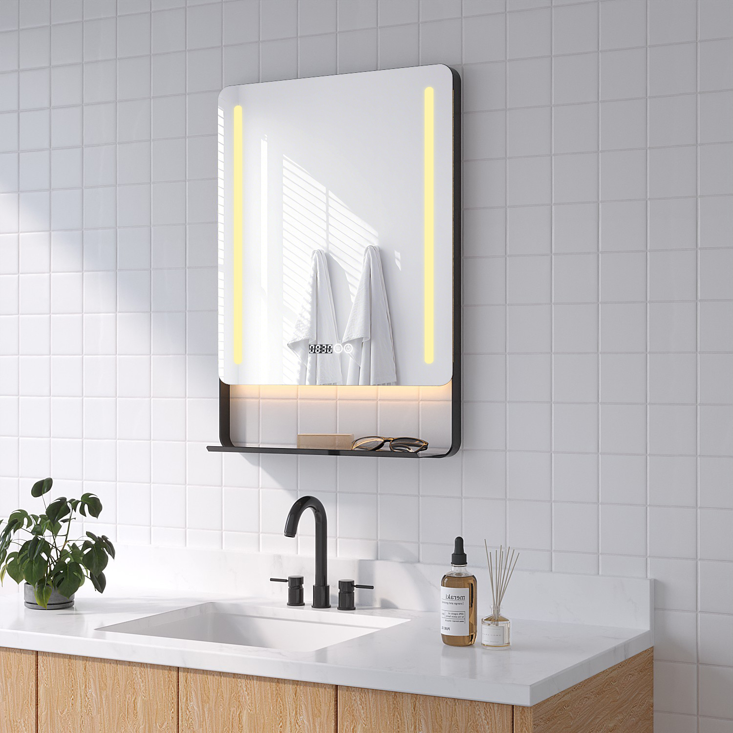 Badezimmerspiegel mit Lichtern, Handtüchern und Ablage. Waschbecken, Wasserhahn und Pflanzen im Vordergrund. Weiße Fliesen an der Wand.