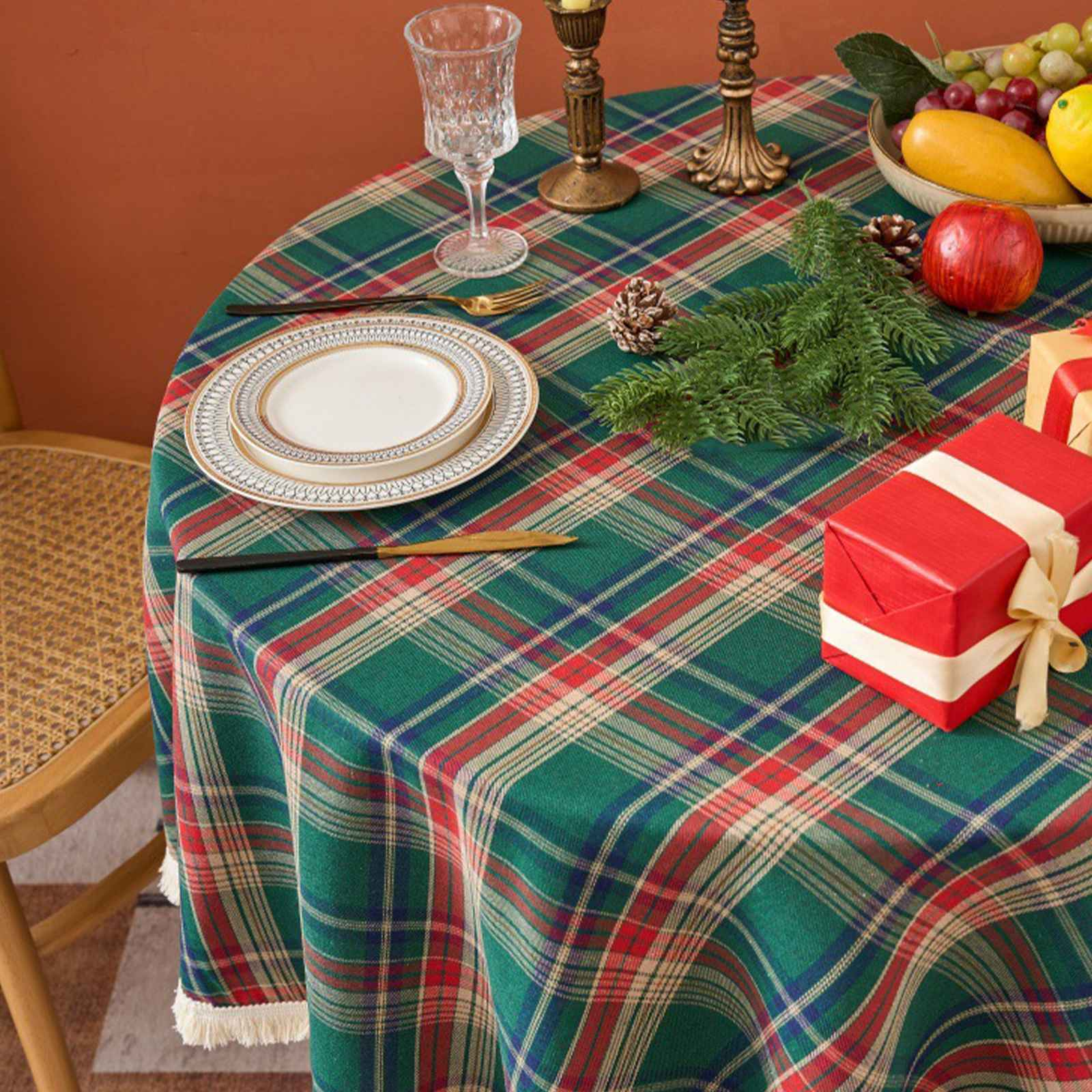Ein Tisch mit einer grünen karierten Tischdecke, Tellern, Glas, Obst und einem Geschenk.