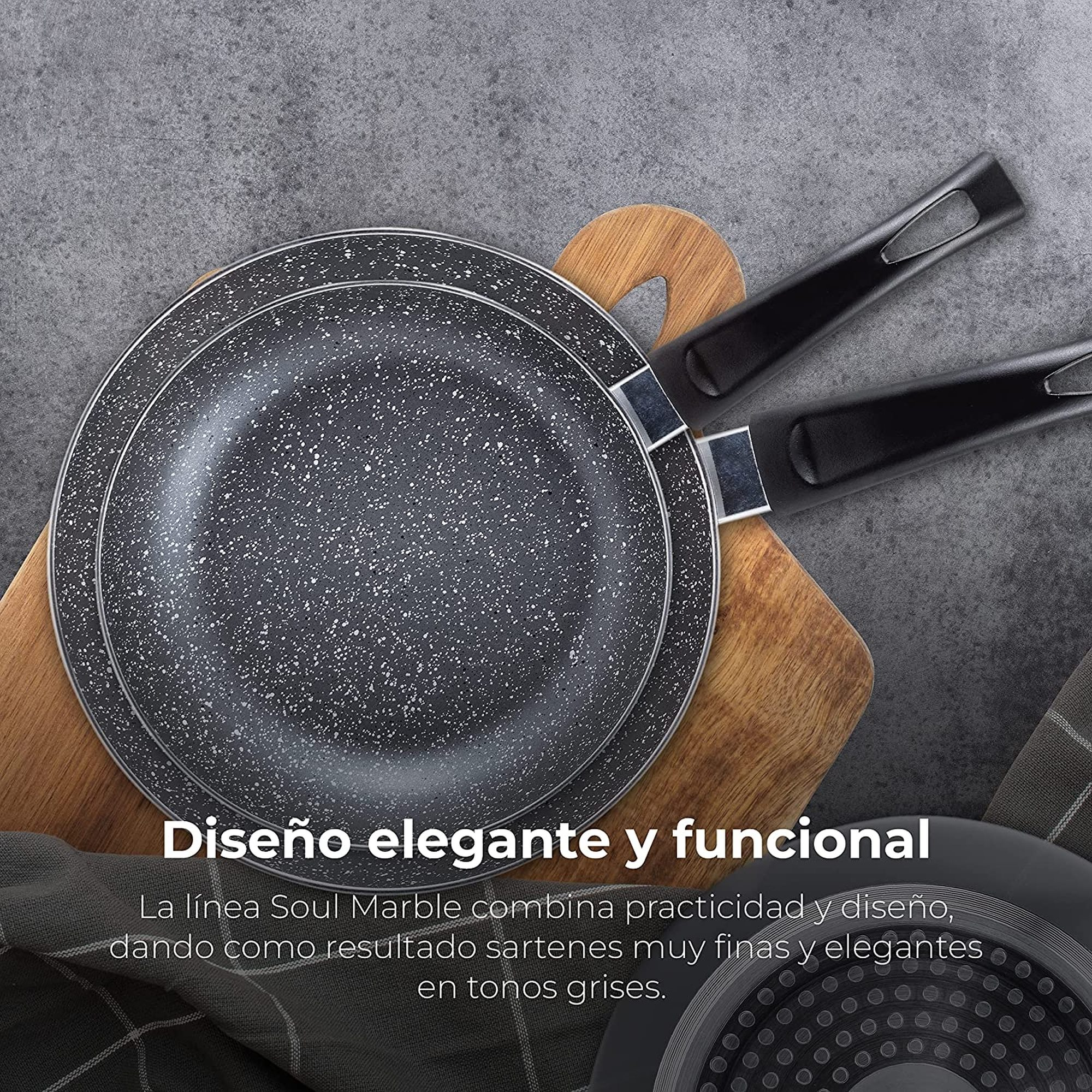 Dos sartenes grises moteadas con asas negras sobre una tabla de madera. El fondo es de piedra gris. Texto en español visible.