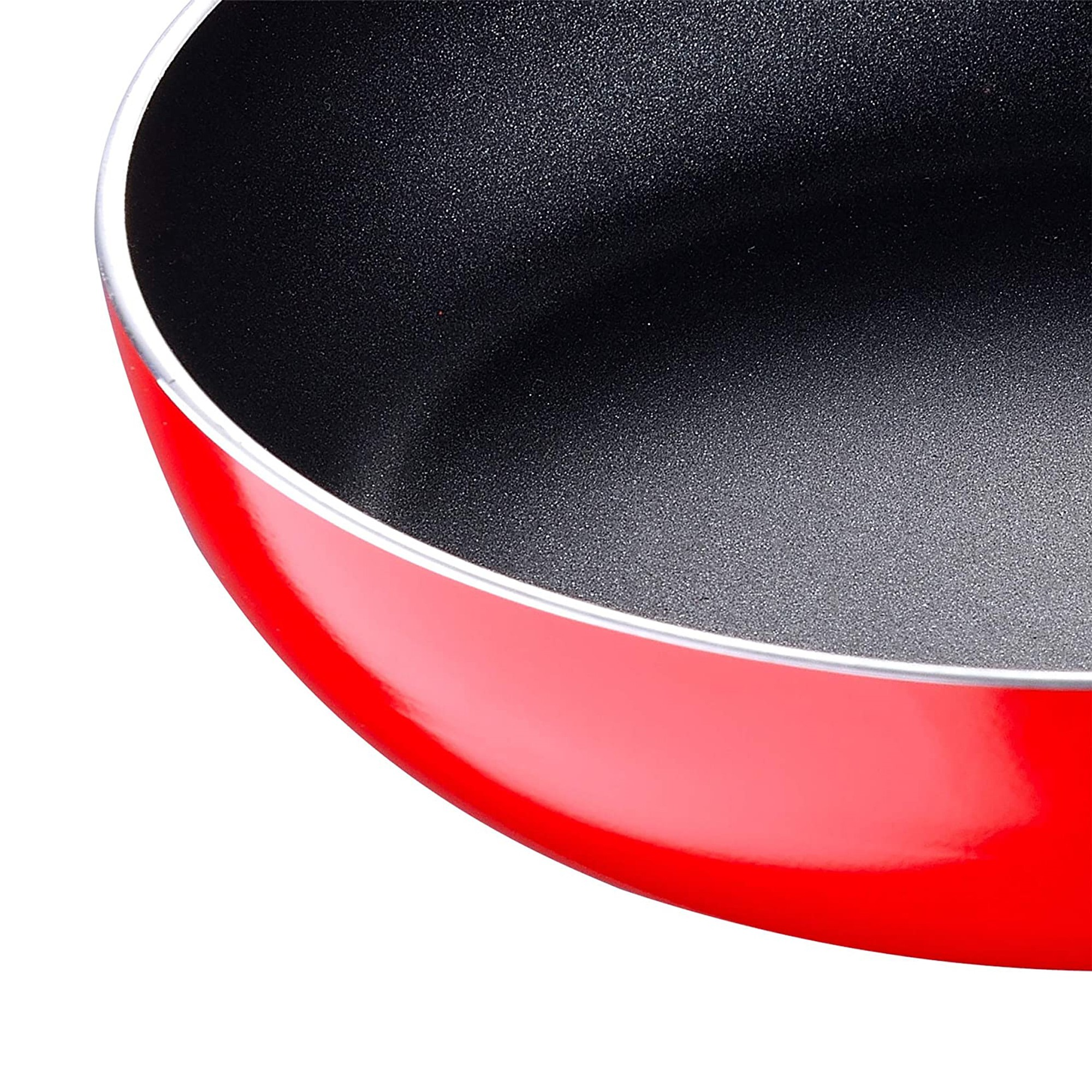 Primer plano de una sartén roja. El interior es negro, con una superficie texturizada. El borde es plateado.