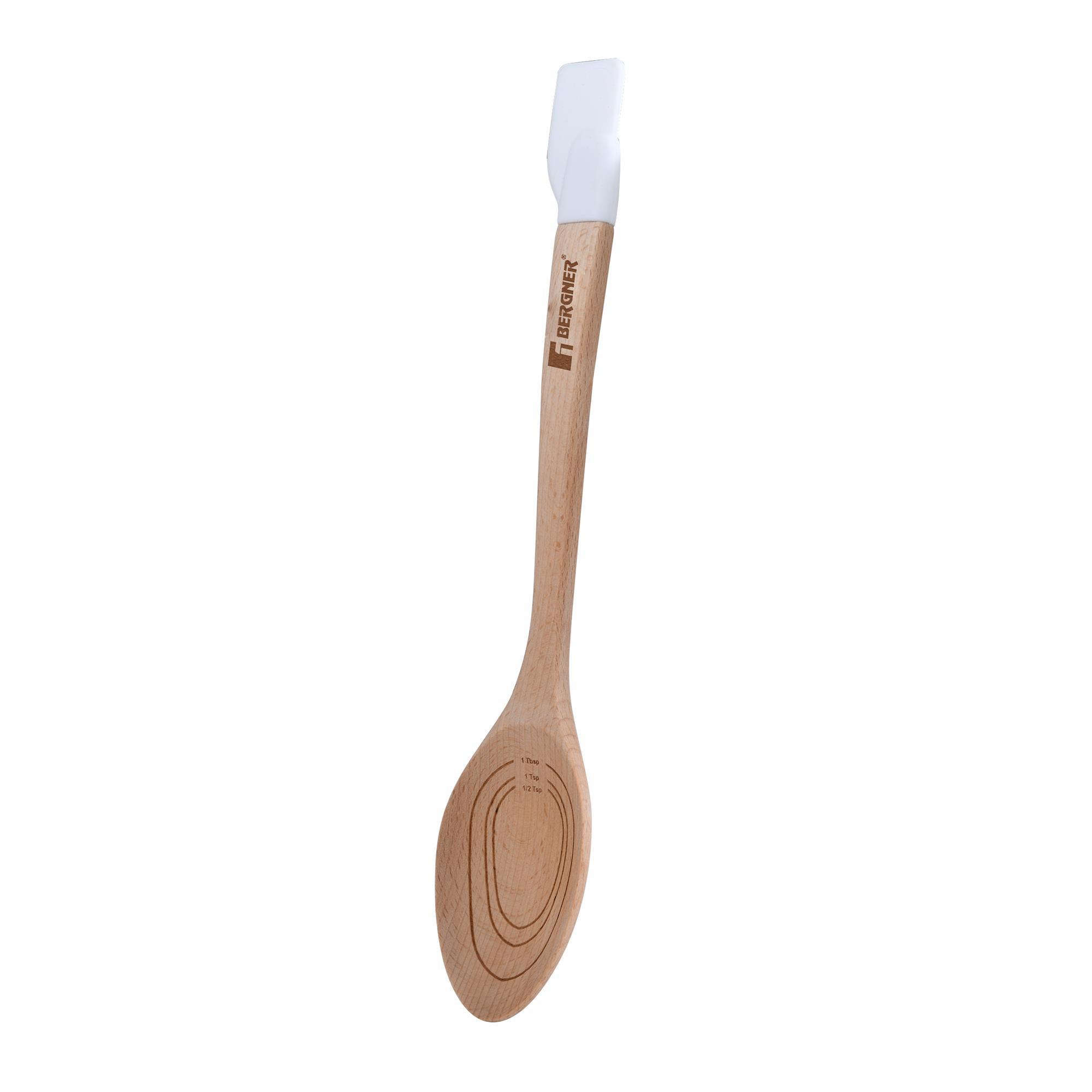 Cuchara de madera con punta de espátula blanca. Tiene marcas de medición en la cabeza de la cuchara. La marca es BERGNER.