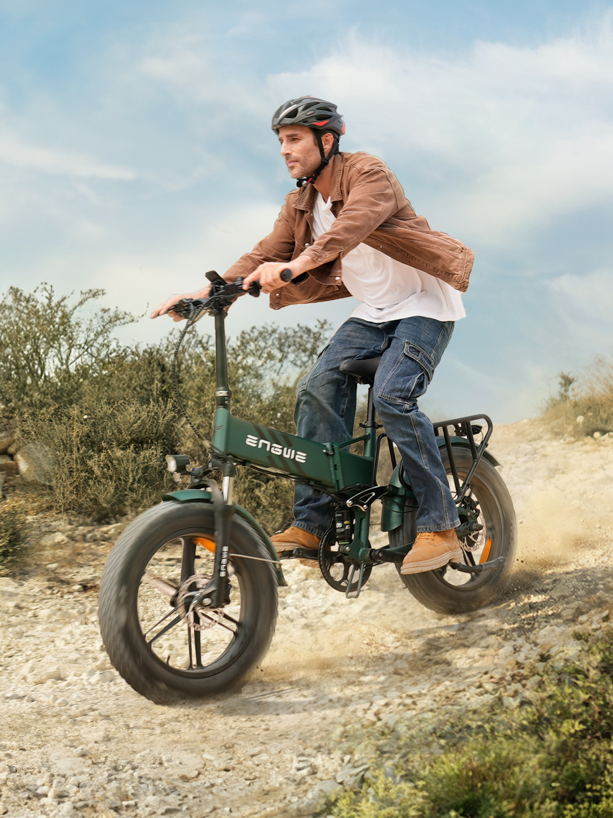 Ein Mann fährt mit einem E-Bike auf einem Feldweg. Er trägt einen Helm und eine braune Jacke. Das Fahrrad ist grün.