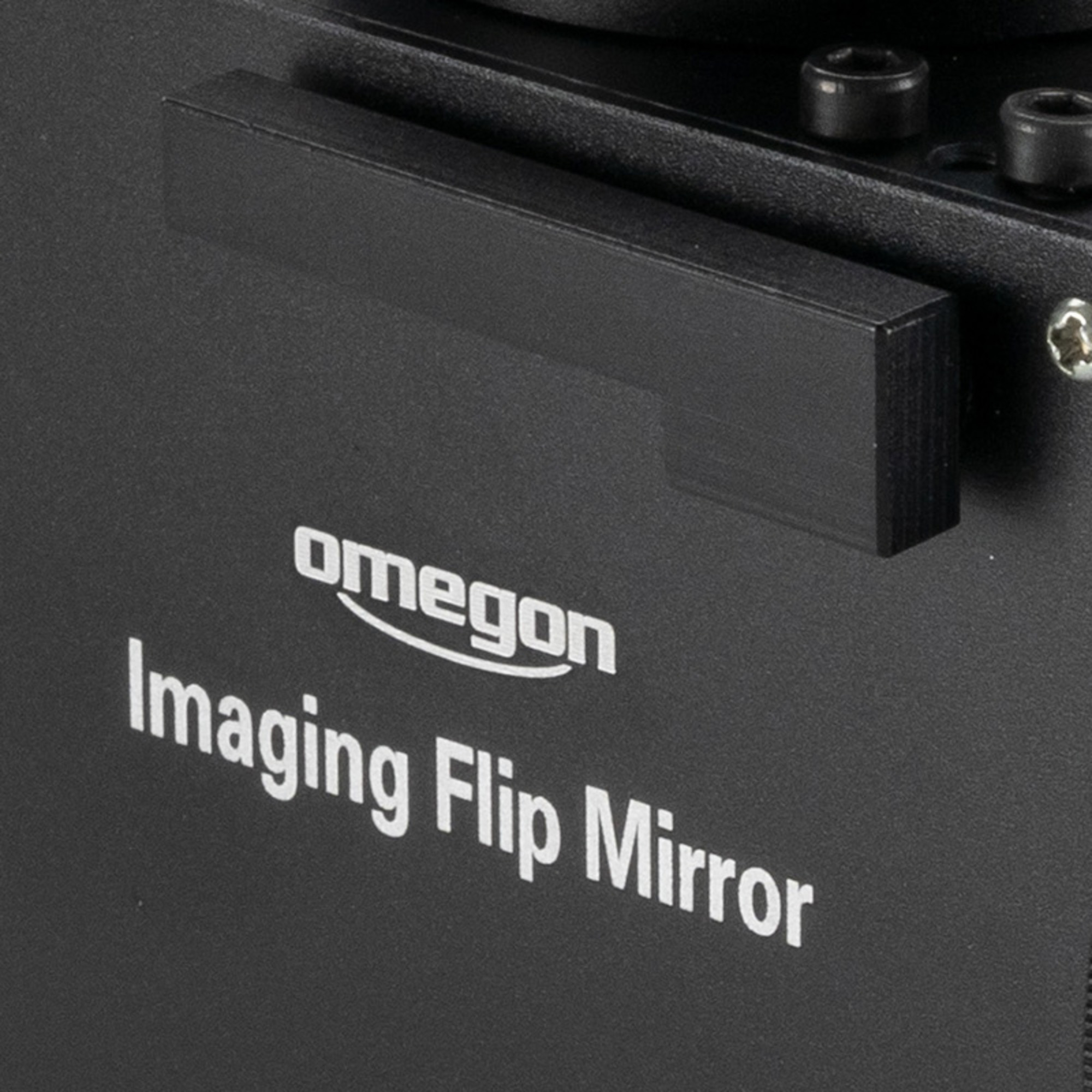 Nahaufnahme eines schwarzen Geräts mit weißem Text: Omegon Imaging Flip Mirror. Oben befindet sich ein schwarzer rechteckiger Griff.