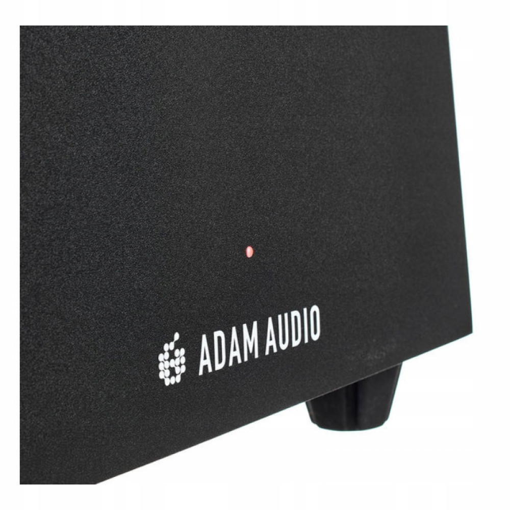 Zbliżenie czarnego głośnika z białym napisem 'ADAM AUDIO'. Świeci się mała czerwona lampka. Widoczna czarna nóżka.