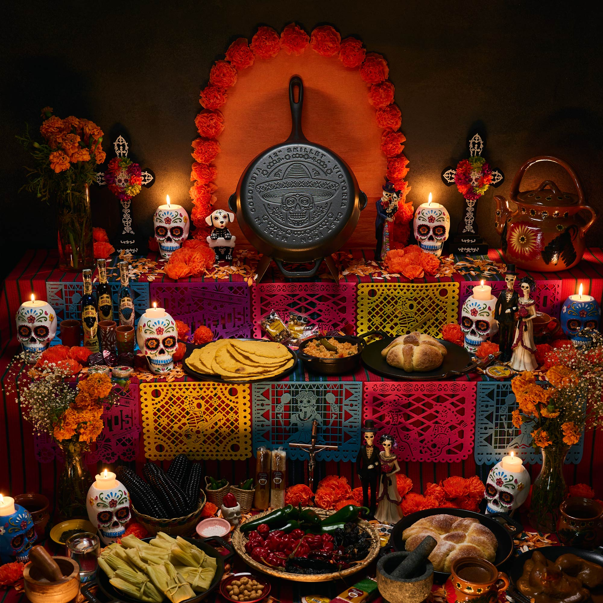 Ein Tag der Toten-Altar mit Essen, Kerzen, Totenköpfen und einer gusseisernen Pfanne.