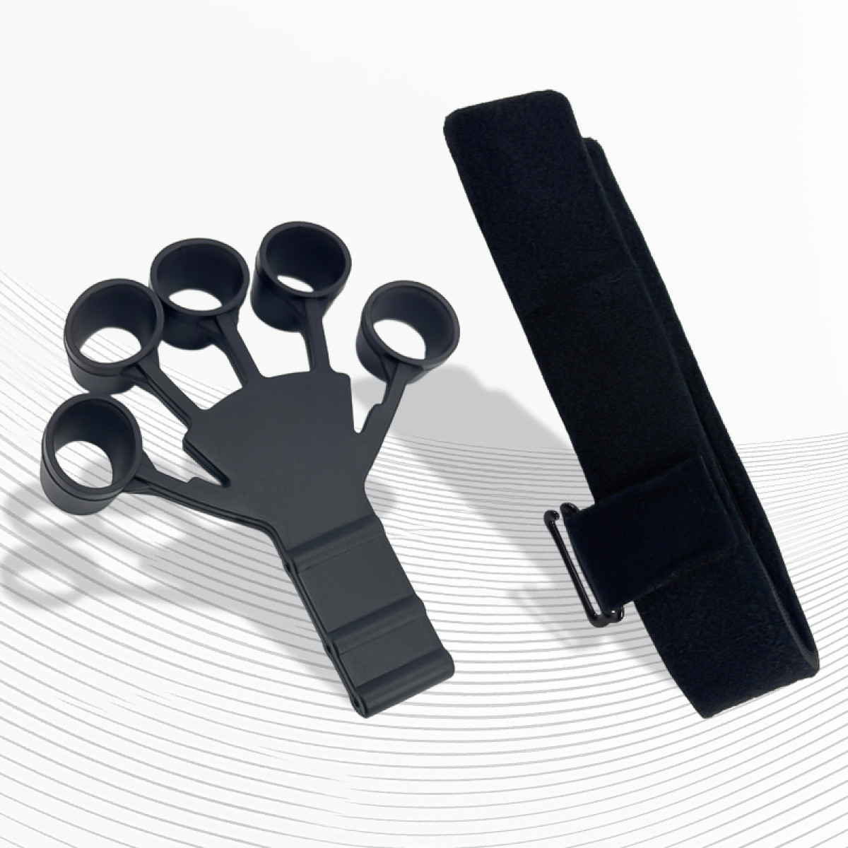 Esercitatore per le mani nero e cinturino nero con fibbia. Entrambi gli oggetti sono su una superficie bianca con sottili linee grigie.