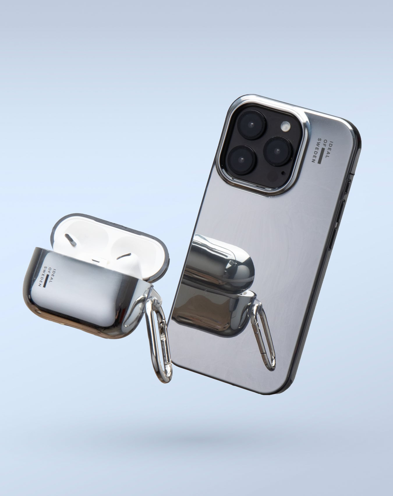 Silbernes iPhone und AirPods-Hülle, beide metallisch. Die Handyhülle spiegelt die AirPods-Hülle wider. Beide schweben vor hellem blauem Hintergrund.