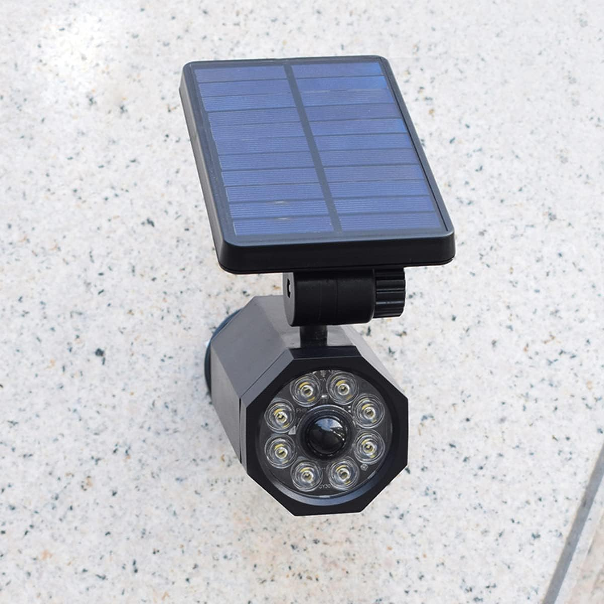 Schwarze Solarleuchte mit blauem Solarpanel, an einer strukturierten, hellgrauen Wand befestigt. Die Leuchte hat mehrere LEDs.