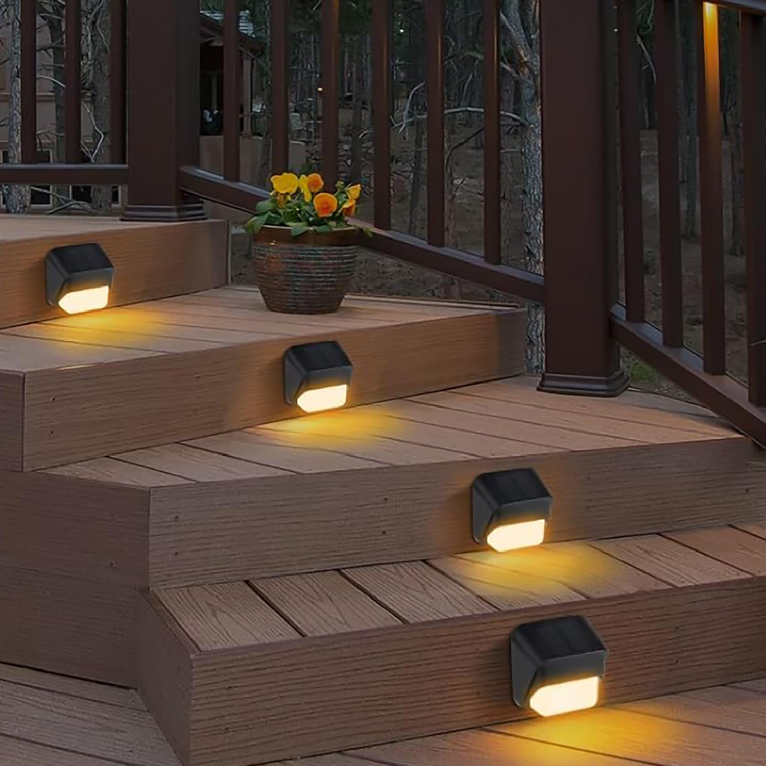 Holzstufen im Freien mit eingebauten Lichtern. Auf der obersten Stufe steht ein Blumentopf. Braunes Geländer rechts, Bäume im Hintergrund.