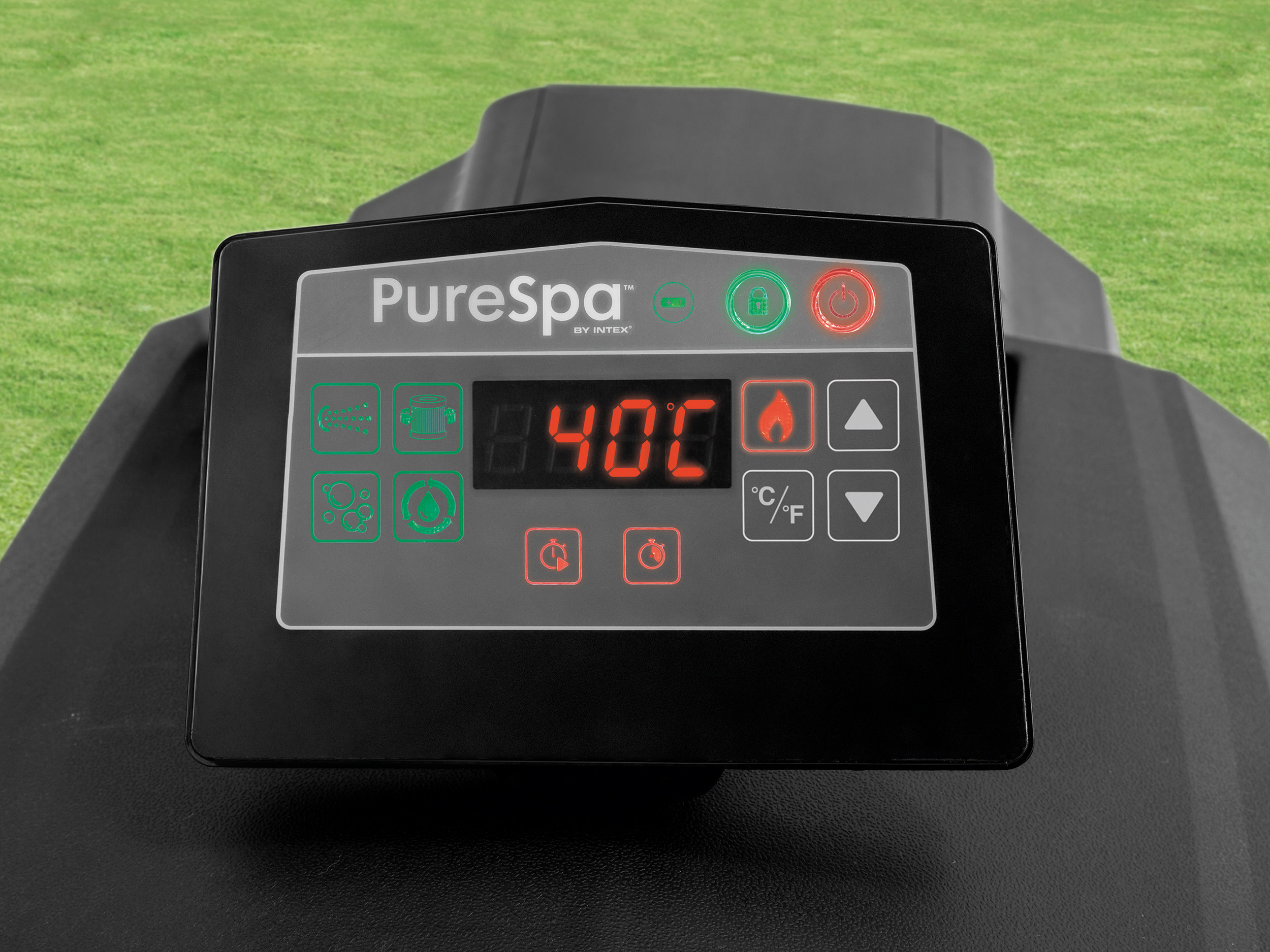 Panel sterowania z czerwonym wyświetlaczem pokazującym 40C, z zielonymi i czerwonymi przyciskami, na czarnej podstawie, zielone tło trawy.