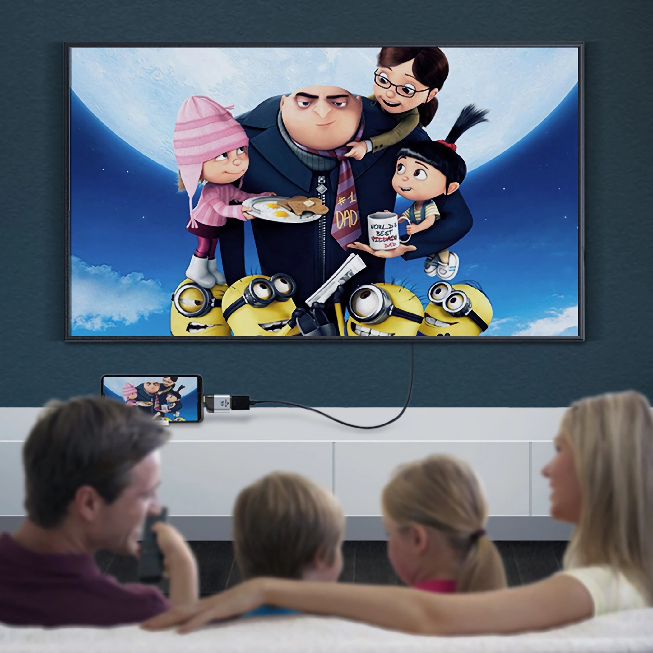 Eine Familie sieht sich einen Film im Fernsehen an. Der Film zeigt Charaktere aus Ich-einfach unverbesserlich. Ein Telefon zeigt dasselbe Bild.