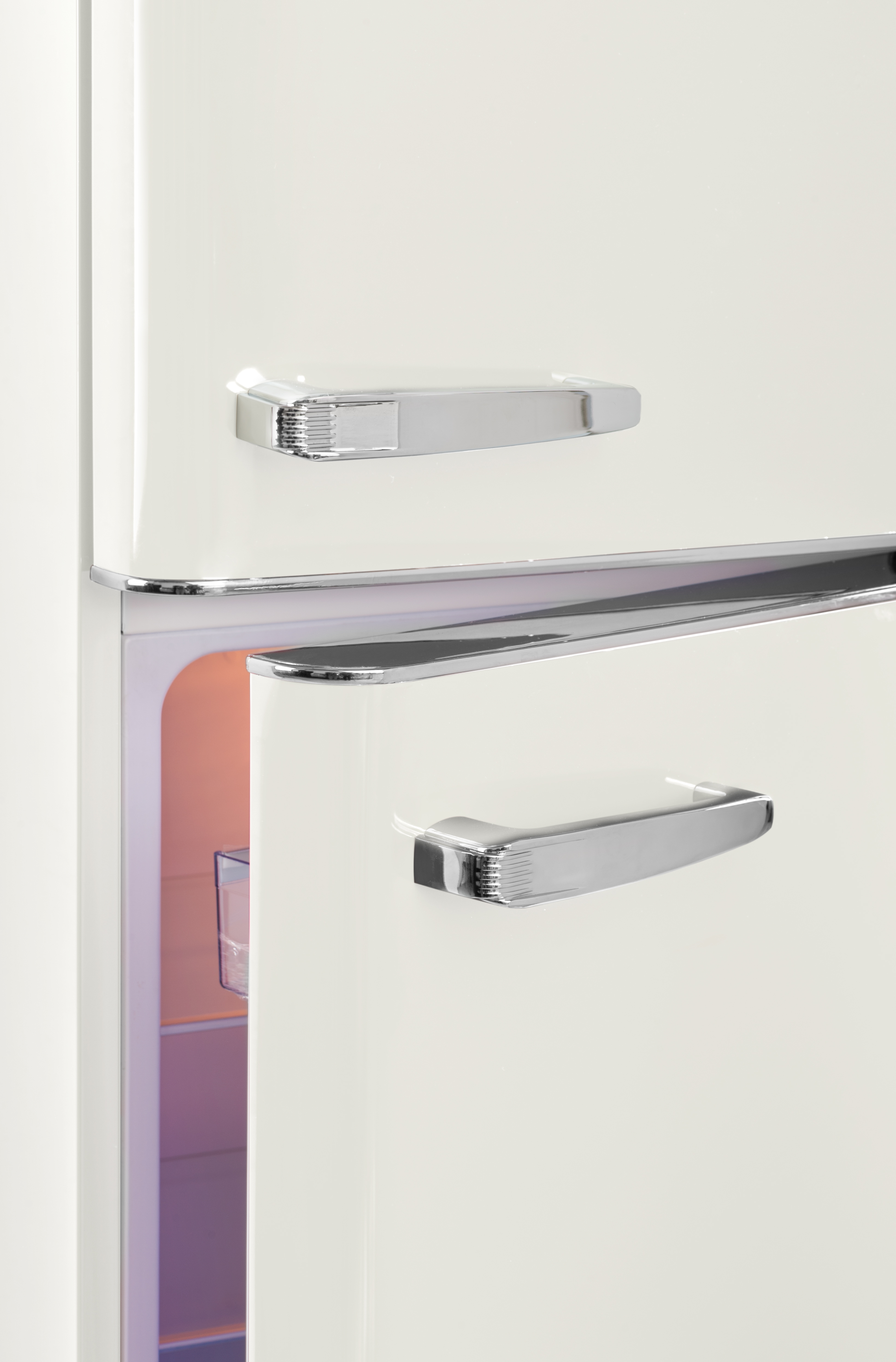 Creme-farbener Retro-Kühlschrank mit Chromgriffen. Die Tür ist angelehnt und gibt das Innere frei.
