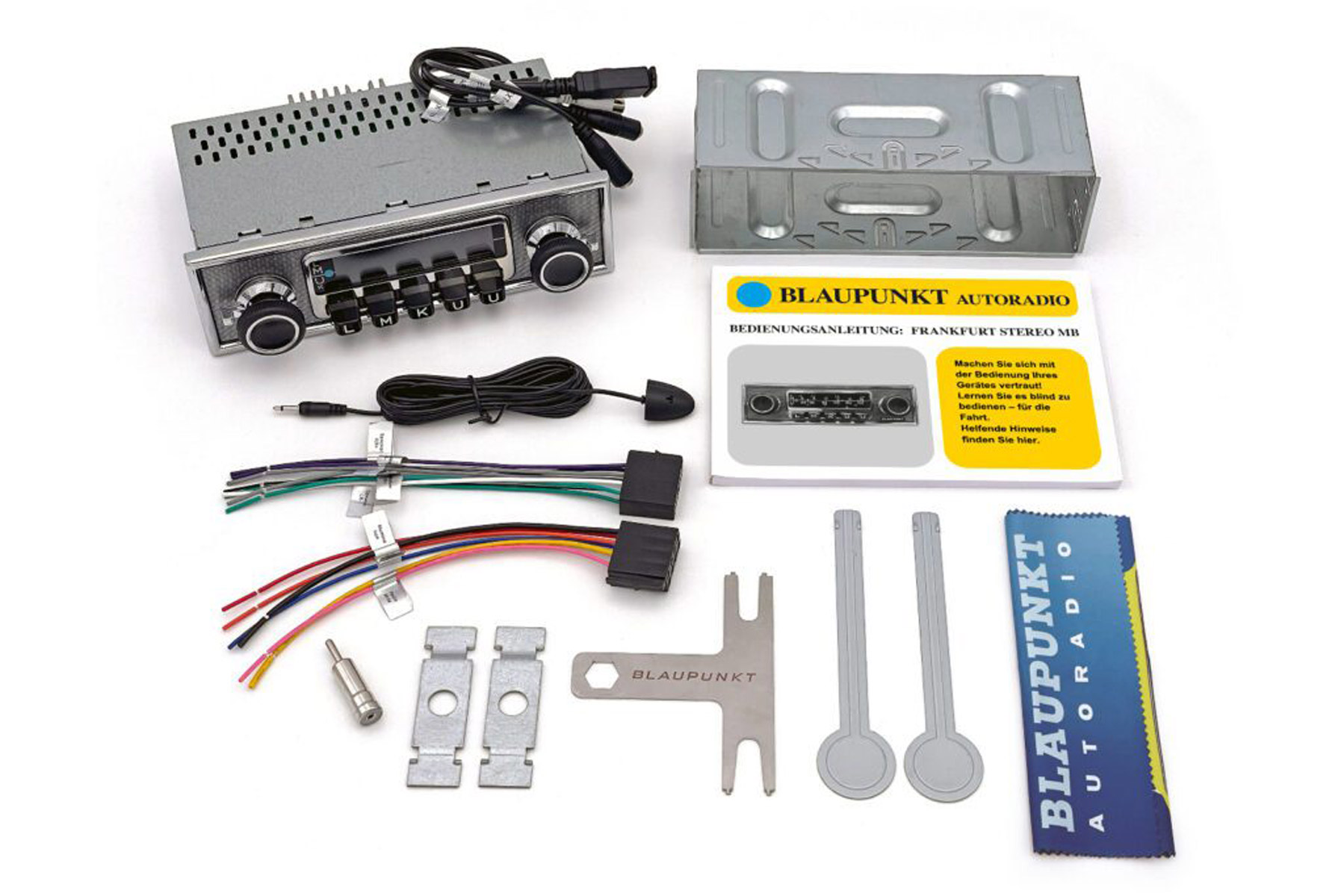 Ein Autoradio-Set mit verschiedenen Komponenten, darunter das Radio, ein Metallgehäuse, Kabel, Handbücher und Werkzeuge, auf weißer Oberfläche.