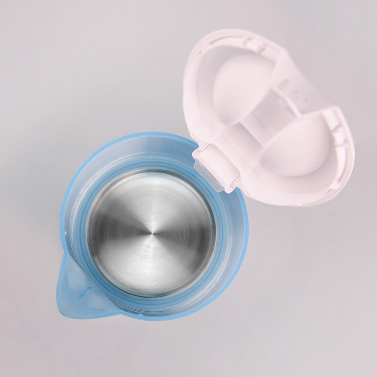 Widok z góry na niebiesko-biały czajnik elektryczny z otwartą pokrywką. Wnętrze jest ze stali nierdzewnej, na szarym tle.