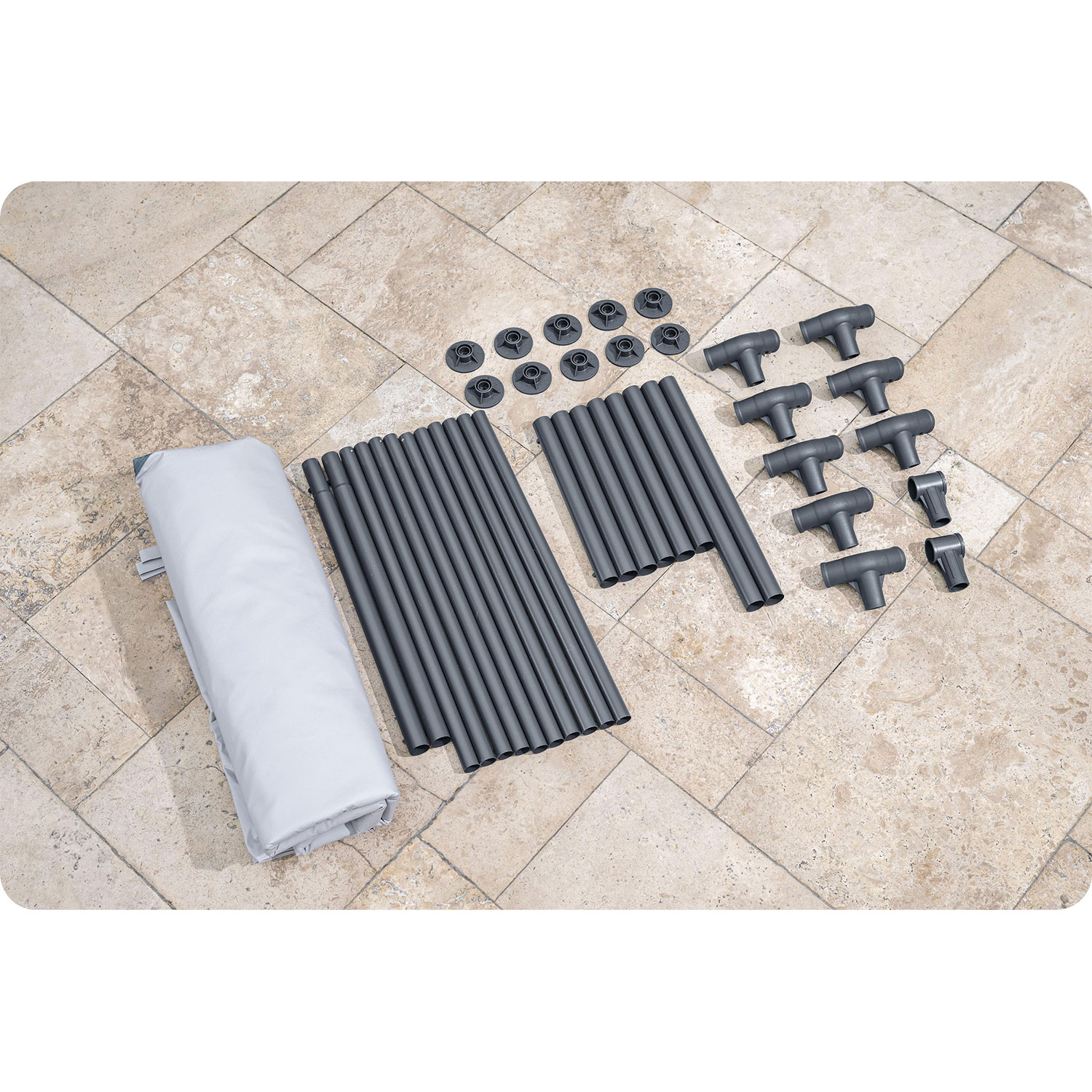 Zdemontowane elementy szarej ramy namiotu. Zawiera słupy, złącza i zwiniętą jasno szarą tkaninę.