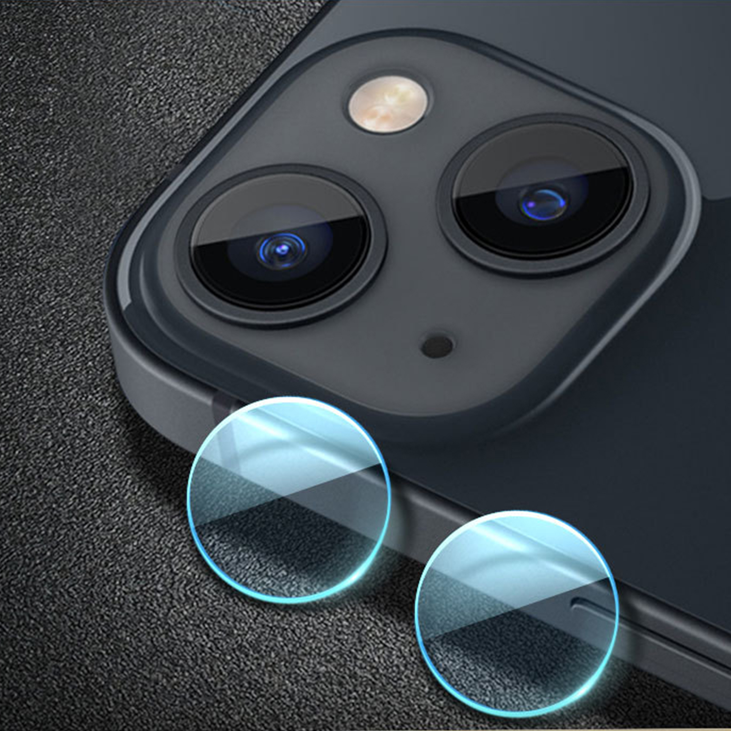 Zbliżenie modułu kamery smartfona z trzema obiektywami i dwiema osłonami ze szkła ochronnego na teksturowanej powierzchni.