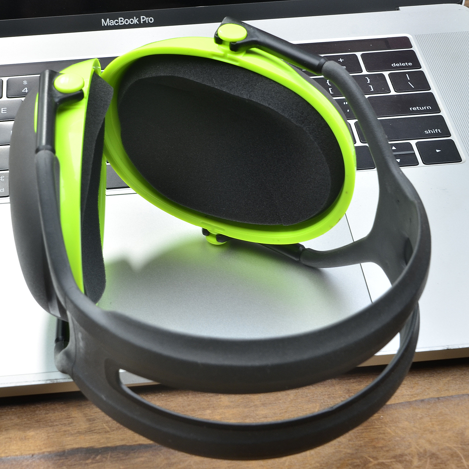 Zielone i czarne nauszniki na klawiaturze laptopa. Nauszniki są otwarte, pokazując czarną wyściółkę.