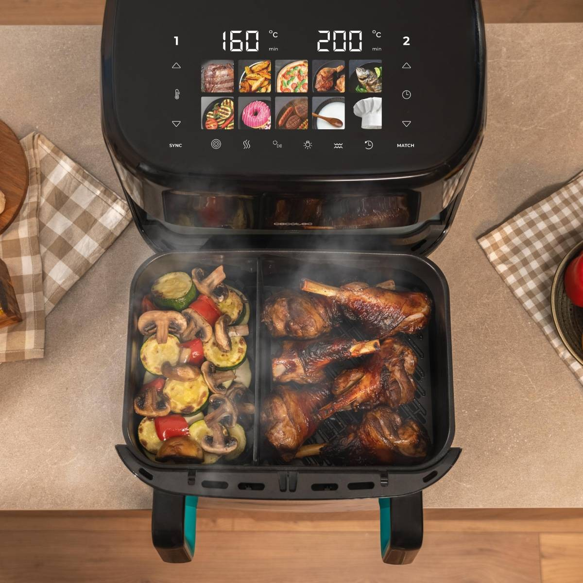 Una freidora de aire con verduras y carne asadas. La pantalla muestra la temperatura y el tiempo de cocción. La freidora está en una encimera.