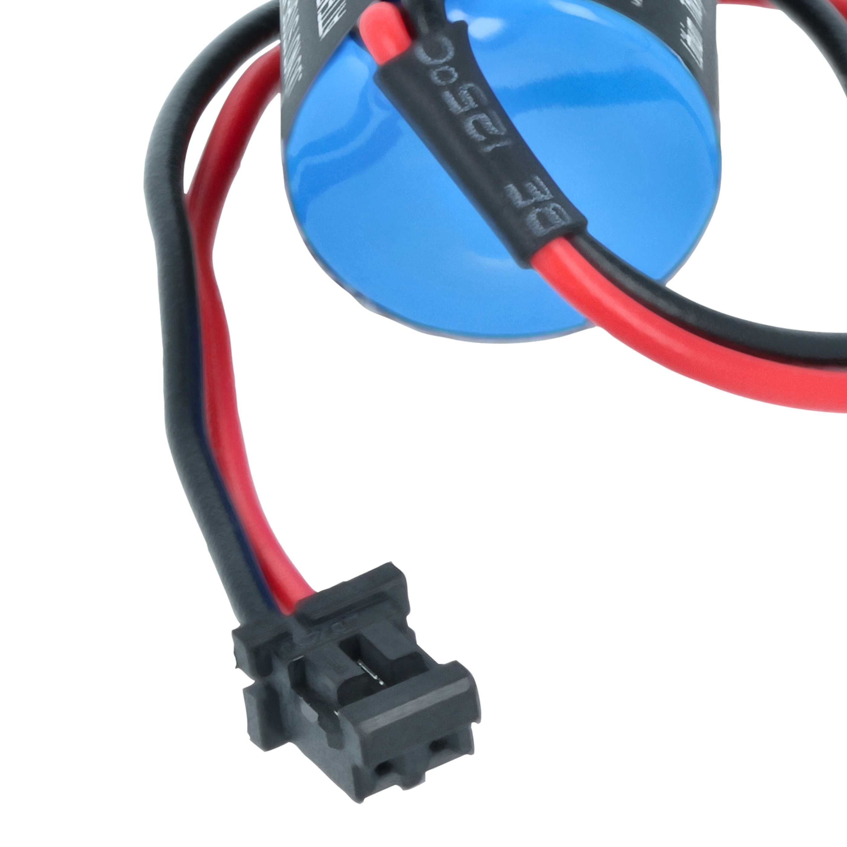 Nahaufnahme eines blauen Zylinders mit Drähten, rot und schwarz, die an einem schwarzen Stecker befestigt sind, vor weißem Hintergrund.
