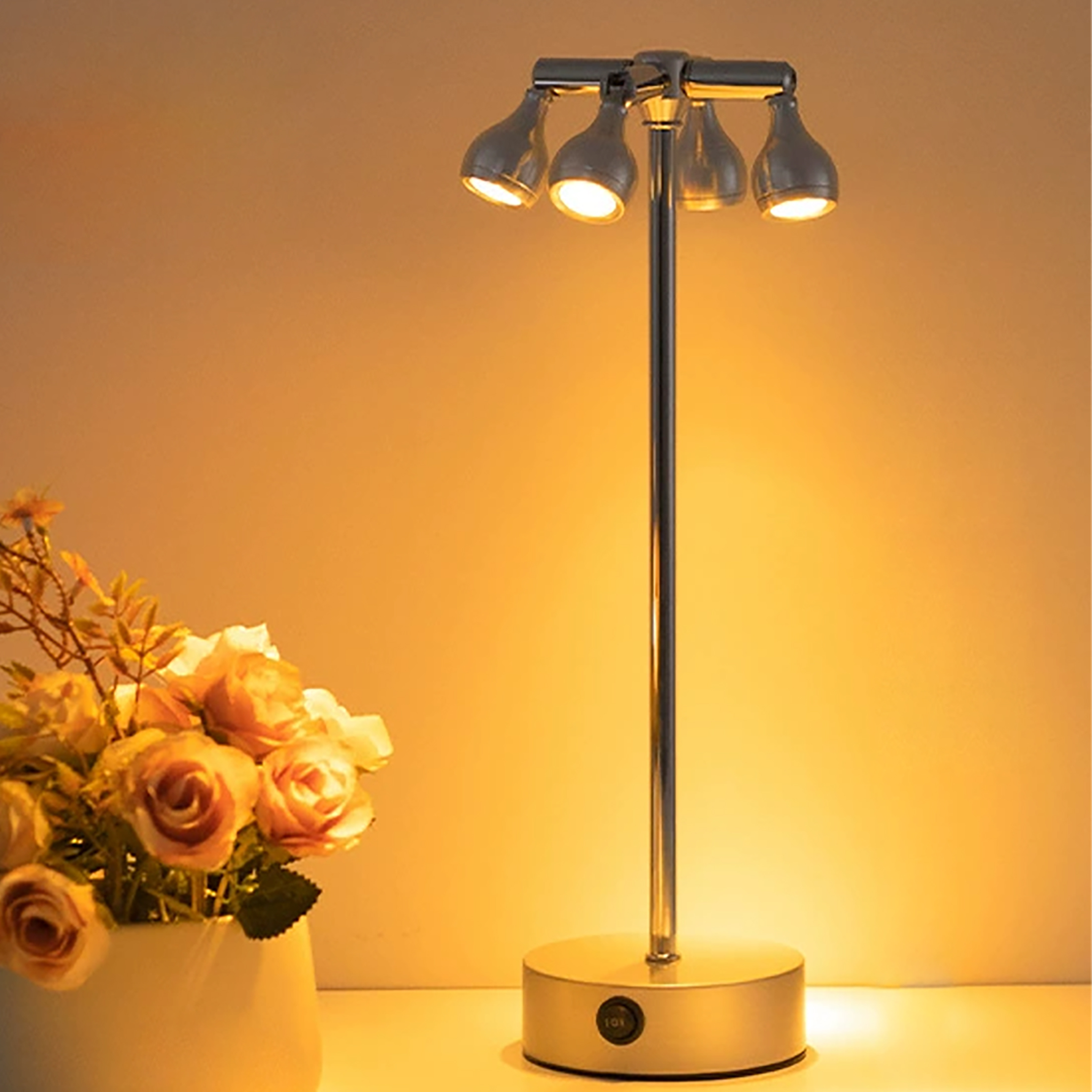 Eine moderne Lampe mit vier Lichtern neben einer Vase mit Rosen. Der Hintergrund ist eine warme Farbe.
