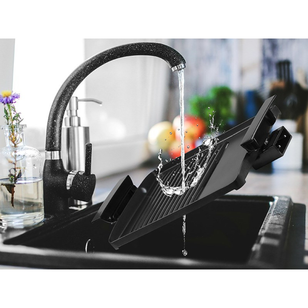 Czarny zlew z czarną baterią. Woda spływa na czarną suszarkę do naczyń. Z lewej strony wazon z kwiatami.