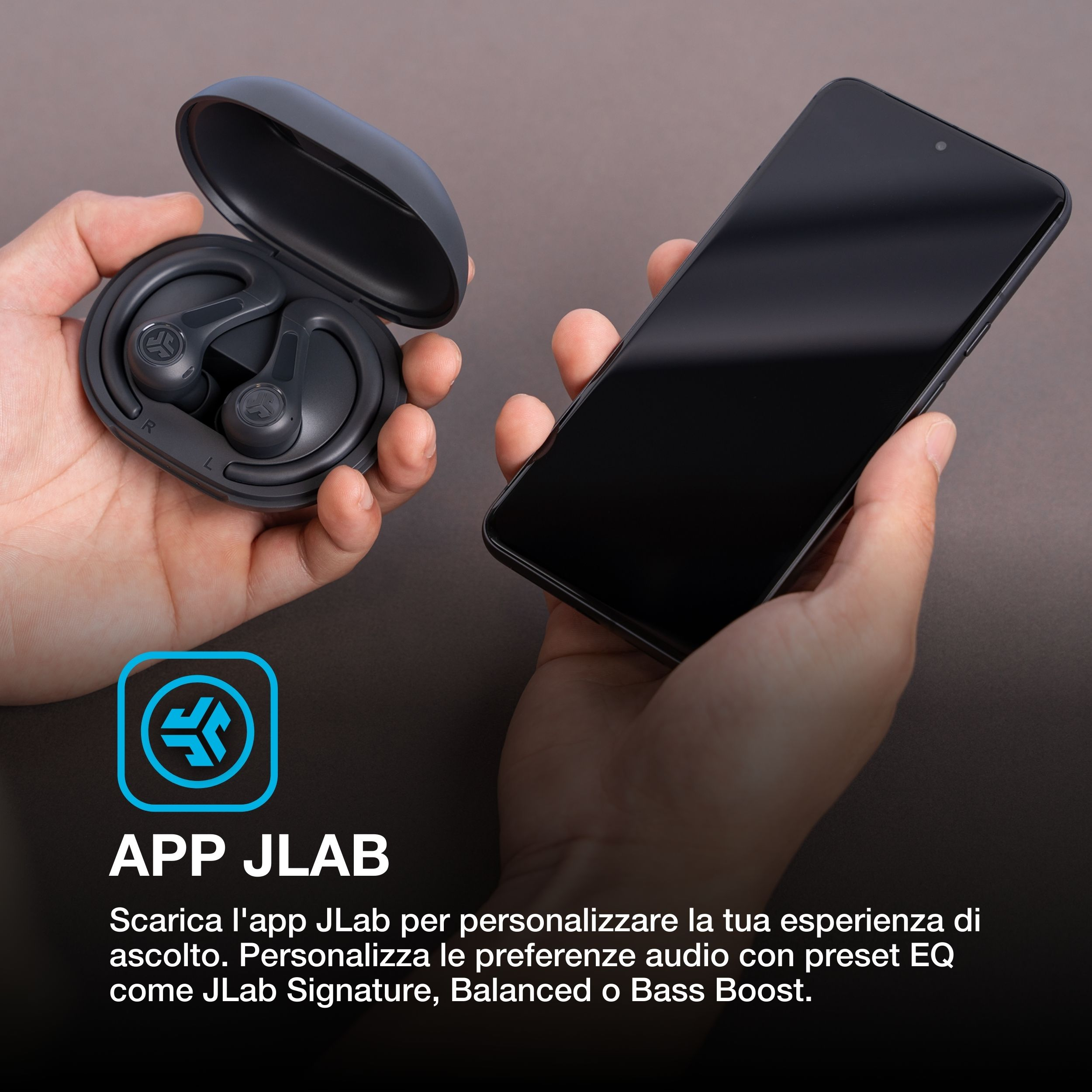 Dłonie trzymają etui na słuchawki i smartfon. Ekran jest ciemny. Logo JLab znajduje się w lewym dolnym rogu.