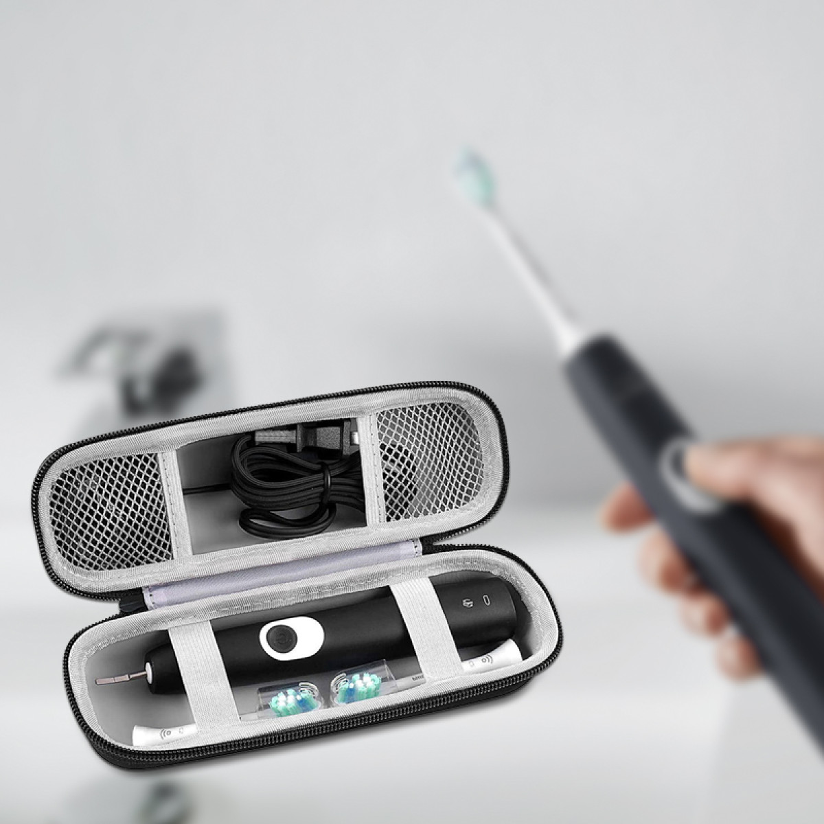 Open toothbrush case with toothbrush, charger, and brush heads. A hand holds a toothbrush in the background. White background.