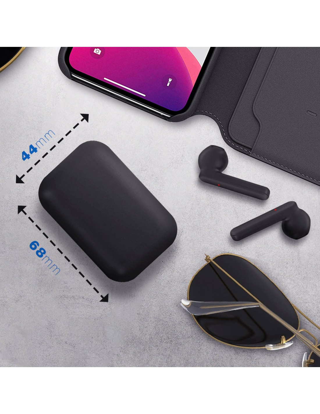 Écouteurs noirs, étui de chargement, téléphone et lunettes de soleil sur une surface grise. Dimensions de l'étui indiquées.