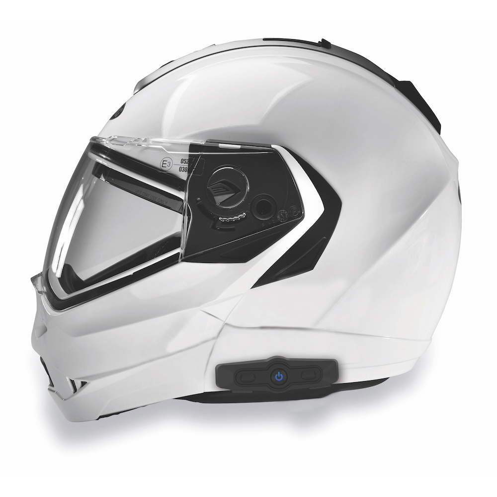 Un casco da moto bianco con visiera trasparente e dettagli neri. Ha un sistema di comunicazione ed è su sfondo bianco.