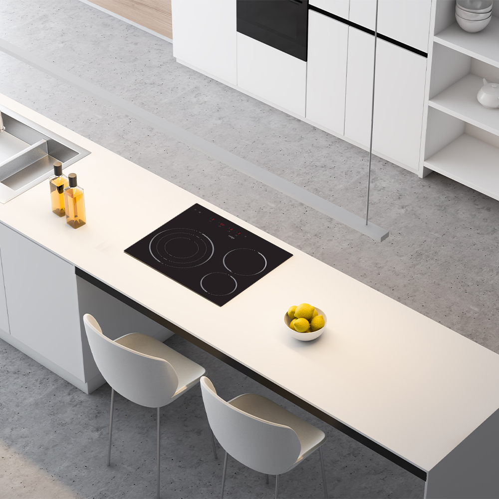 Una isla de cocina moderna con una placa de cocina negra, un cuenco de limones, dos sillas blancas y armarios blancos al fondo.