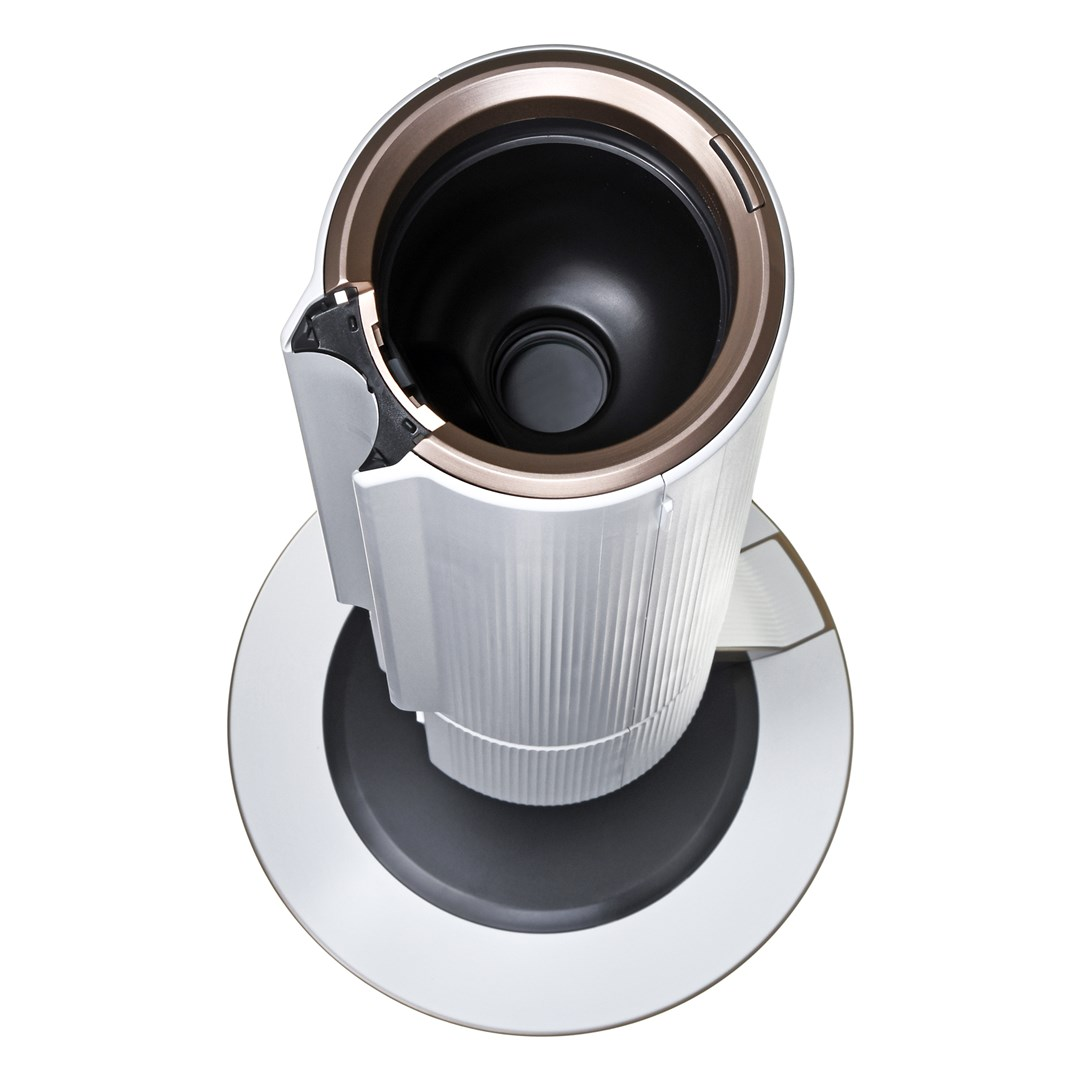 Widok z góry na biało-złoty ekspres do kawy. Ma cylindryczny korpus z żebrami i stoi na srebrnej podstawie.