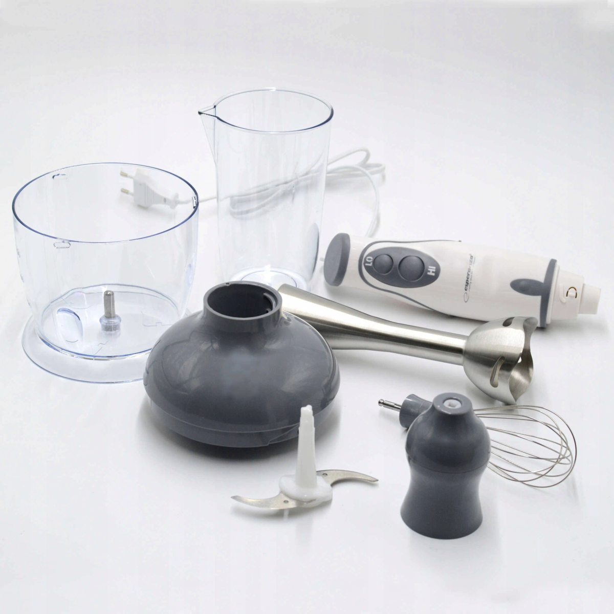 Zdemontowany blender ręczny na białej powierzchni. Elementy to silnik, końcówki do blendowania, miska i dzbanek.