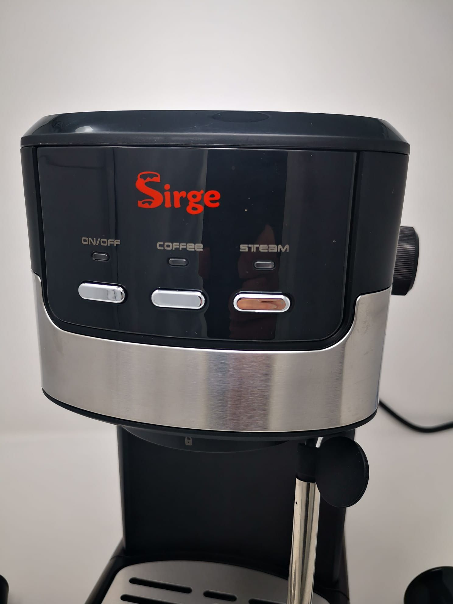 Macchina per espresso Sirge nera e argento. Ha pulsanti on/off, caffè e vapore. Il logo è rosso.