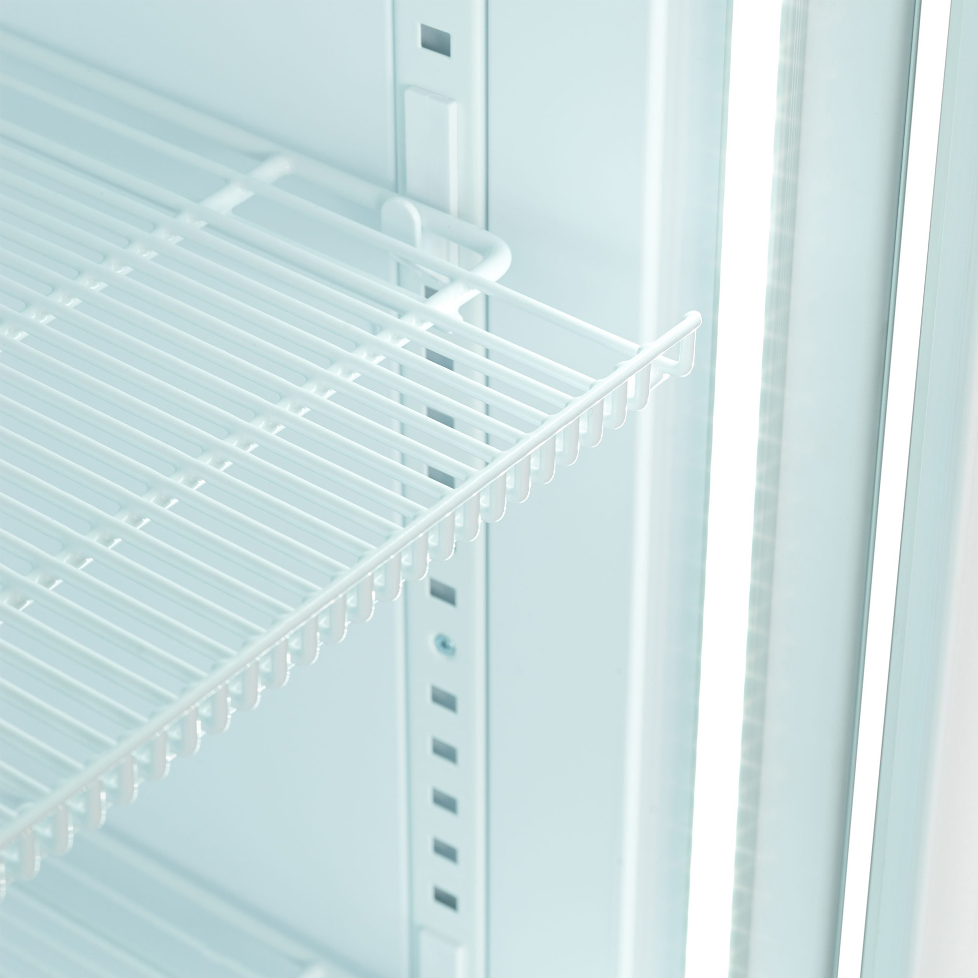 Nahaufnahme eines weißen Drahtregals im Kühlschrank. Der Hintergrund ist das hellblaue Innere des Kühlschranks.