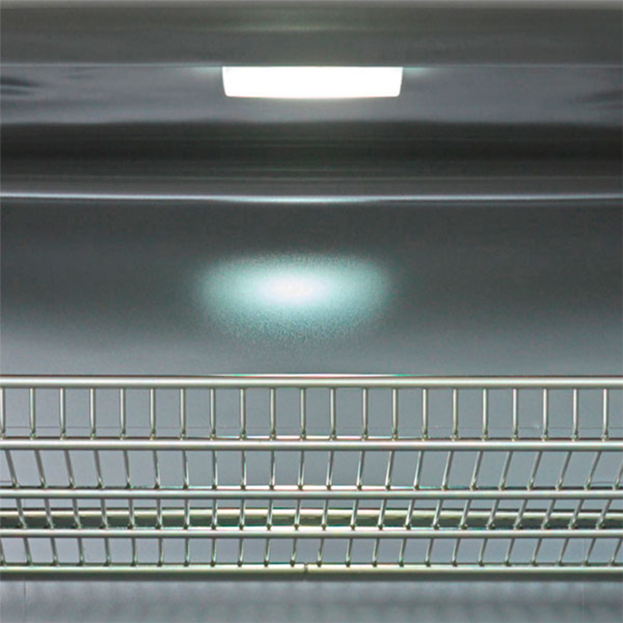 Ein Metallgeschirrkorb befindet sich unter einem hellen Licht. Der Hintergrund ist eine glänzende, reflektierende Oberfläche.