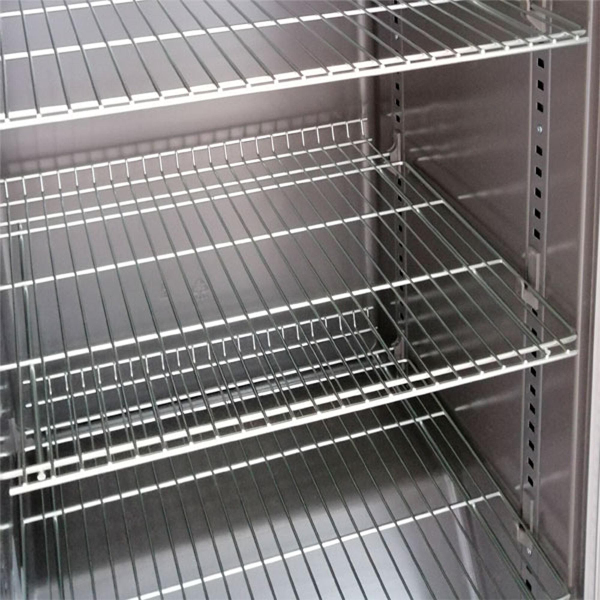 In einem Metallschrank befinden sich mehrere Drahtregale. Die Regale sind horizontal angeordnet, die Seiten des Schranks sind sichtbar.