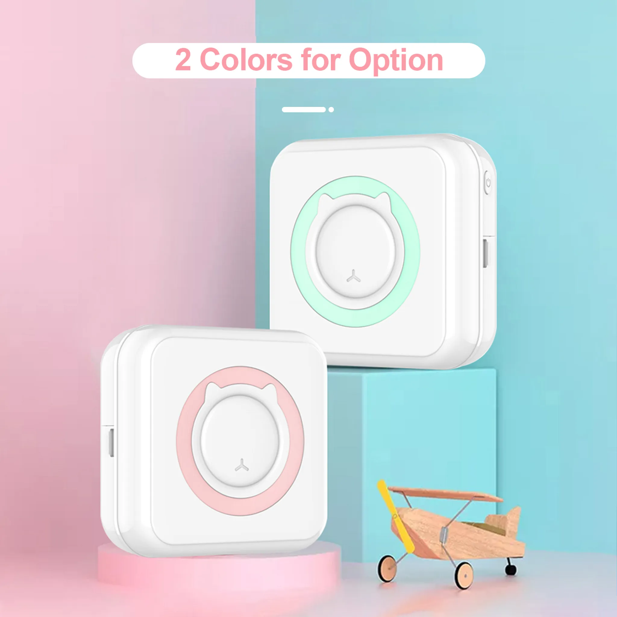 Zwei weiße Drucker mit Katzen-Gesicht-Design, rosa und grüne Akzente, auf rosa und blauem Hintergrund, mit einem Holzspielzeugflugzeug.