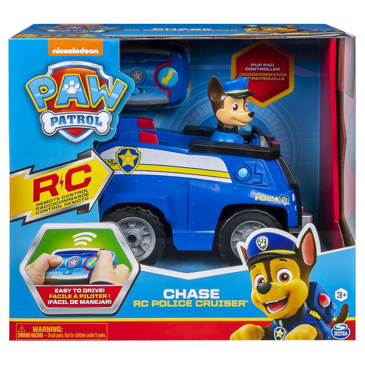 Un juguete de patrulla canina Chase RC policía cruiser está en una caja. Es azul con una raya amarilla y una figura de Chase.