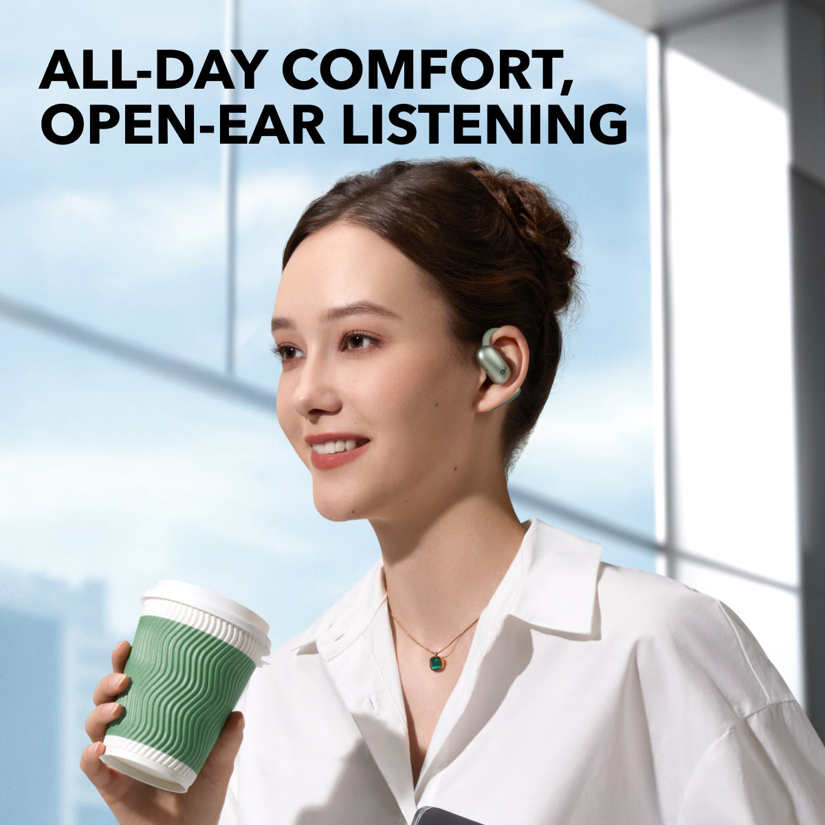 Una mujer con auriculares sonríe, sosteniendo una taza de café. El texto dice 'Comodidad todo el día, escucha de oído abierto'.