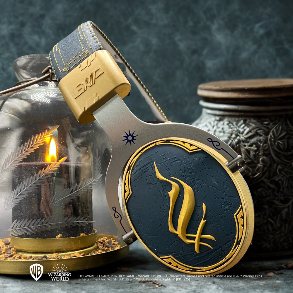Kopfhörer mit gold-blauem Design, eine brennende Kerze und ein Glas im Hintergrund. Auf den Kopfhörern steht das Wort 'ENIC'.
