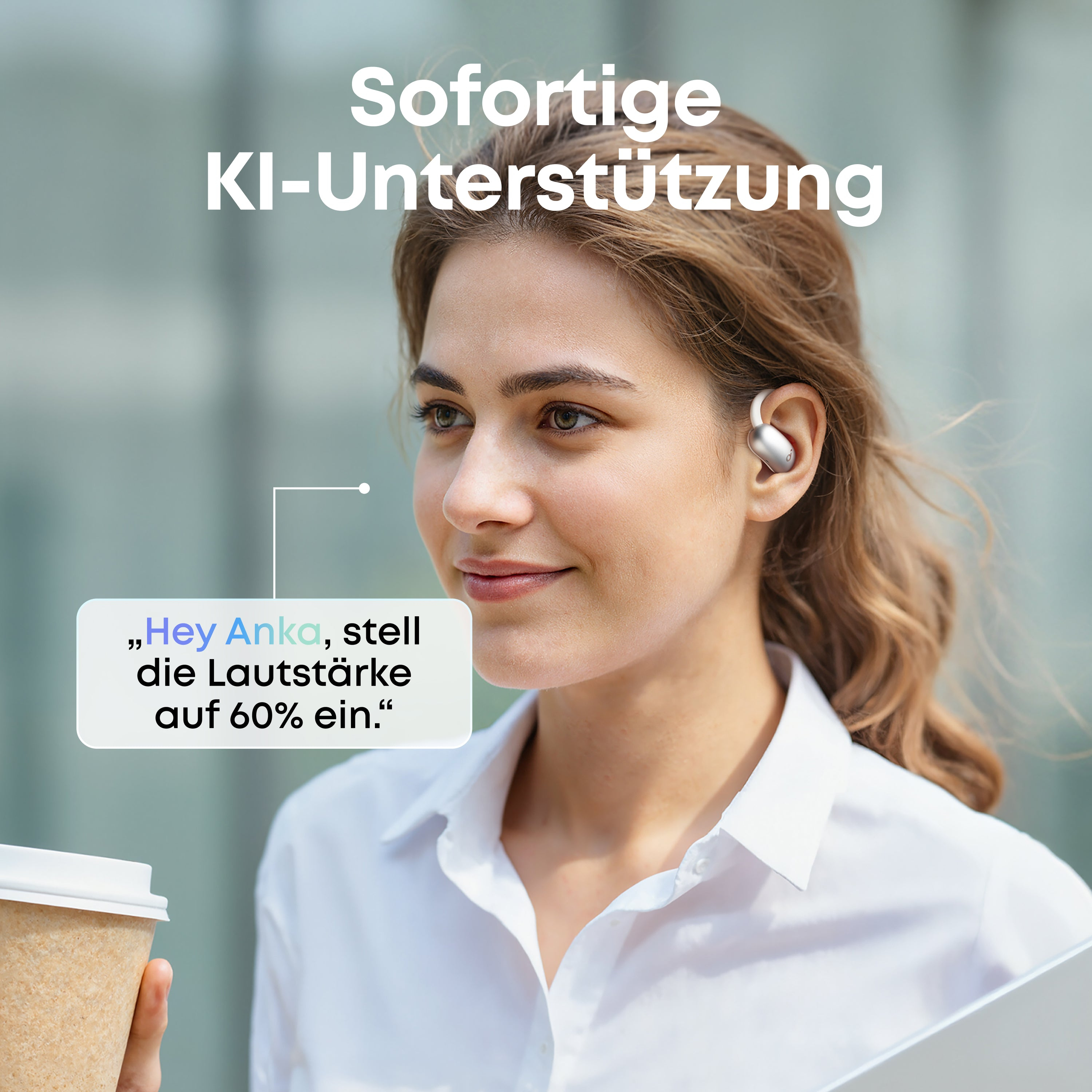 Kobieta z wkładką douszną, trzymająca filiżankę kawy. Nakładka tekstowa mówi: Hej Anka, ustaw głośność na 60%.