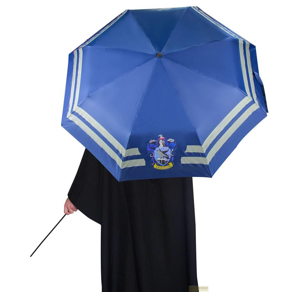 Persona sosteniendo un paraguas azul de Ravenclaw con rayas blancas. La persona lleva una túnica negra y sostiene una varita.