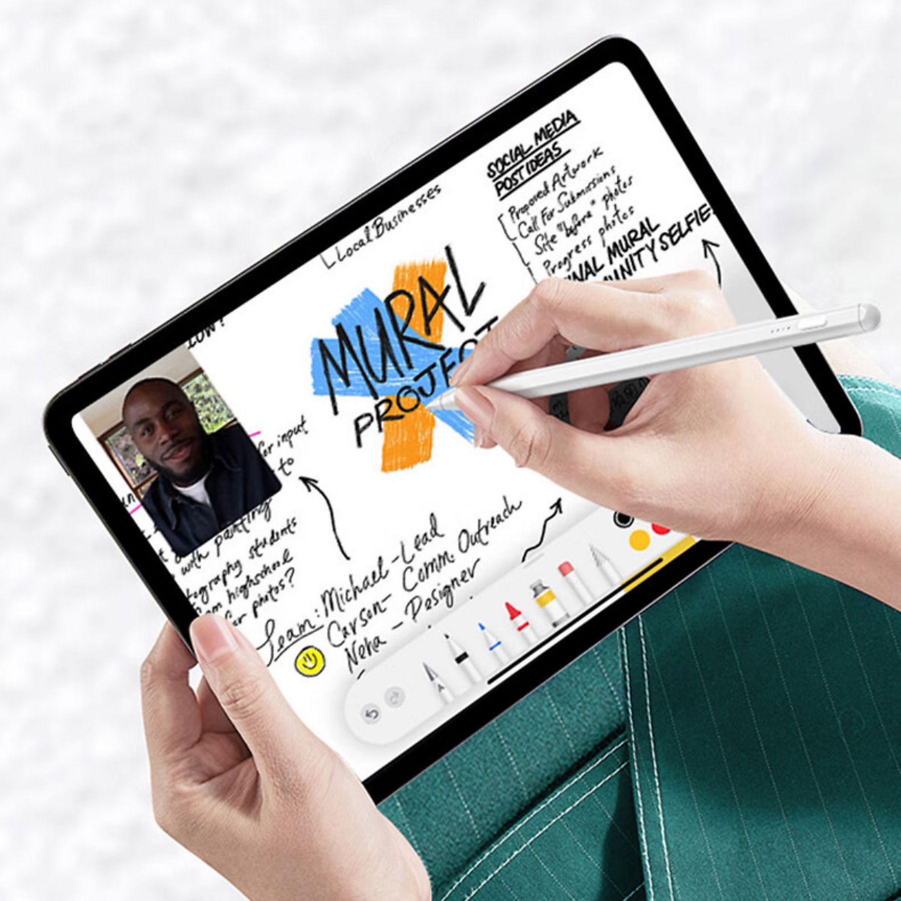 Eine Person hält ein Tablet mit einem Stift. Das Tablet zeigt Notizen zu einem Wandprojekt und ein Foto eines Mannes.