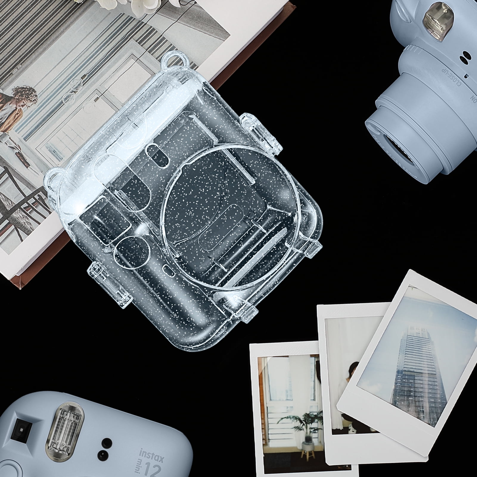 Eine hellblaue Instax Mini 12 Kamera mit einer transparenten Hülle und Fotos auf schwarzem Untergrund.